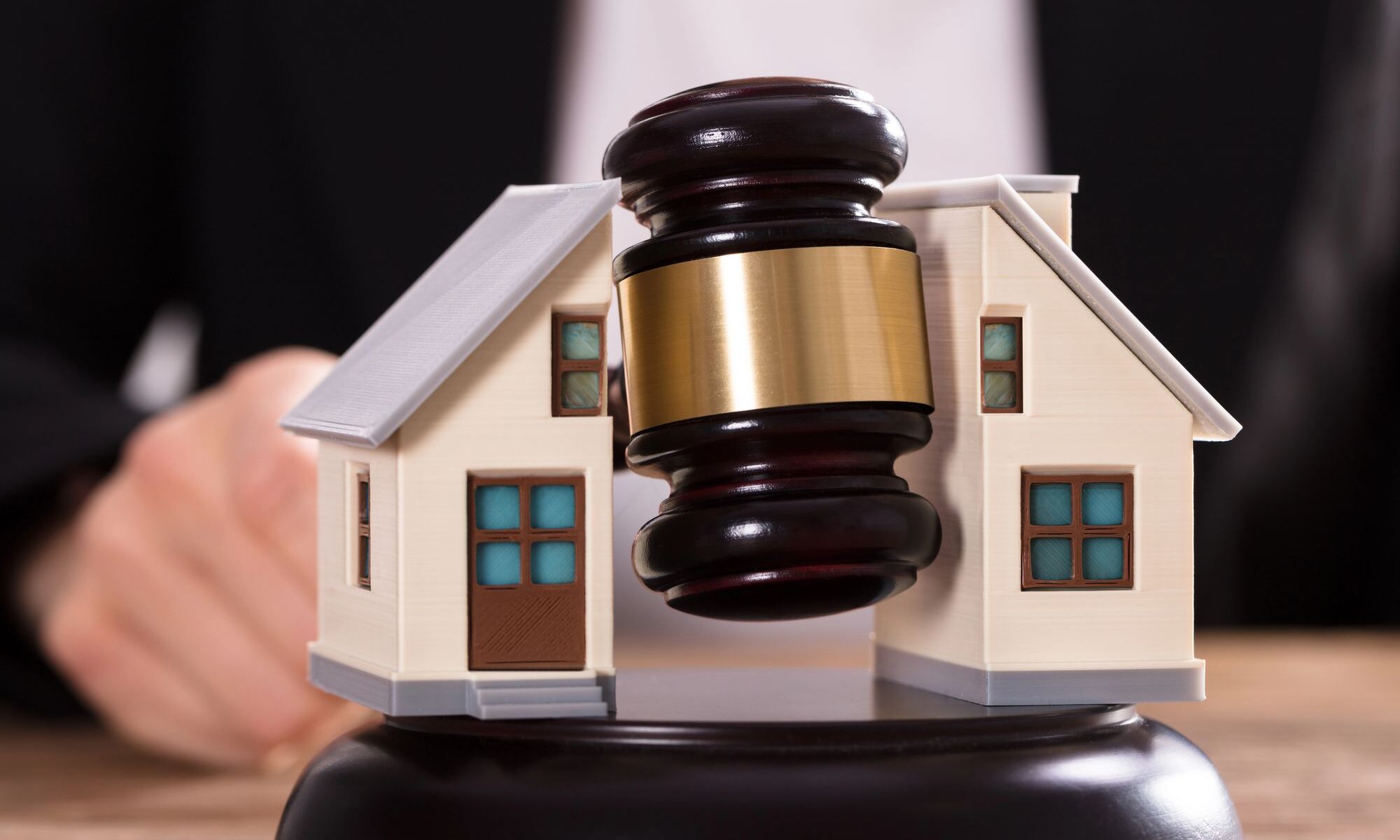 Richterhammer zwischen zwei Hausmodellen – Symbolbild für Immobilienaufteilung bei Scheidung